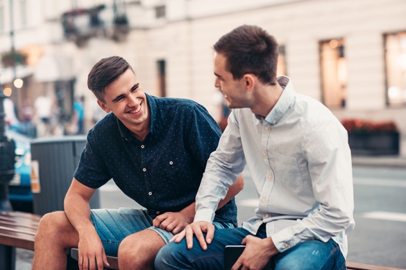 Friends talking together on a bench in the city - Can Aries Men Be Secretive