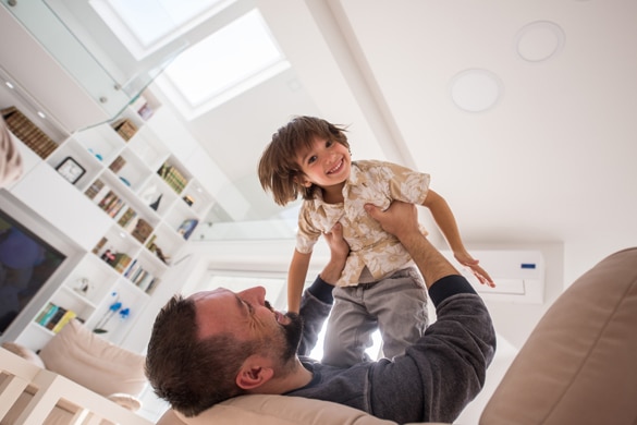 Cheerful young boy having fun with father on sofa - Reasons to Get Involved with an Aries Man